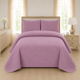 Mauve dusty pink quilted 3-piece bed spread set with two matching pillow shams on a made bed