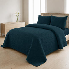 Teal blue quilted 3-piece bed spread set with two matching pillow shams on a made bed