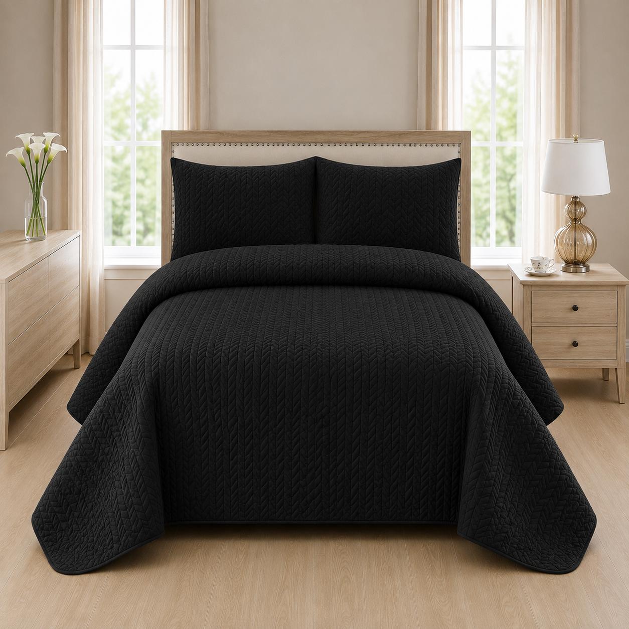 Black quilted 3-piece bed spread set with two matching pillow shams on a made bed