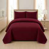 Maroon quilted 3-piece bed spread set with two matching pillow shams on a made bed