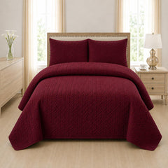 Maroon quilted 3-piece bed spread set with two matching pillow shams on a made bed
