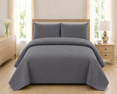 Grey quilted 3-piece bed spread set with two matching pillow shams on a made bed