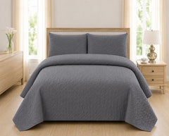 Grey quilted 3-piece bed spread set with two matching pillow shams on a made bed