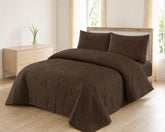 Chocolate brown quilted 3-piece bed spread set with two matching pillow shams on a made bed