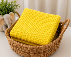 Yellow honeycomb waffle baby blanket folded in a nursery basket