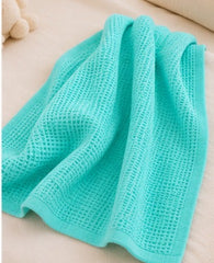Turquoise honeycomb waffle baby blanket draped on a bed