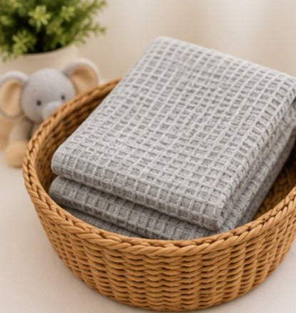 Light grey honeycomb waffle cotton baby blanket folded in a basket