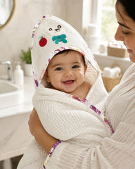 Mother holding baby in the teddy and apple hooded towel in the bathroom