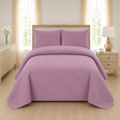 Mauve dusty pink quilted 3-piece bed spread set with two matching pillow shams on a made bed