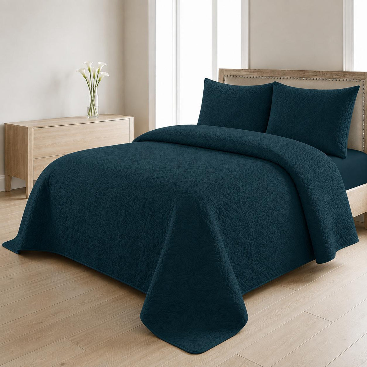 Teal blue quilted 3-piece bed spread set with two matching pillow shams on a made bed