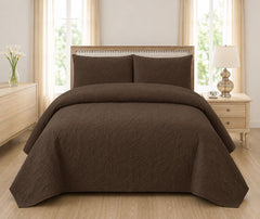 Chocolate brown quilted bedspread styled on a bed in a cosy neutral bedroom