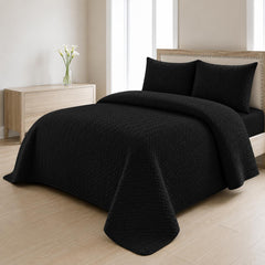 Black quilted bedspread styled on a bed in a cosy neutral bedroom