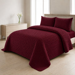 Maroon quilted bedspread styled on a bed in a cosy neutral bedroom