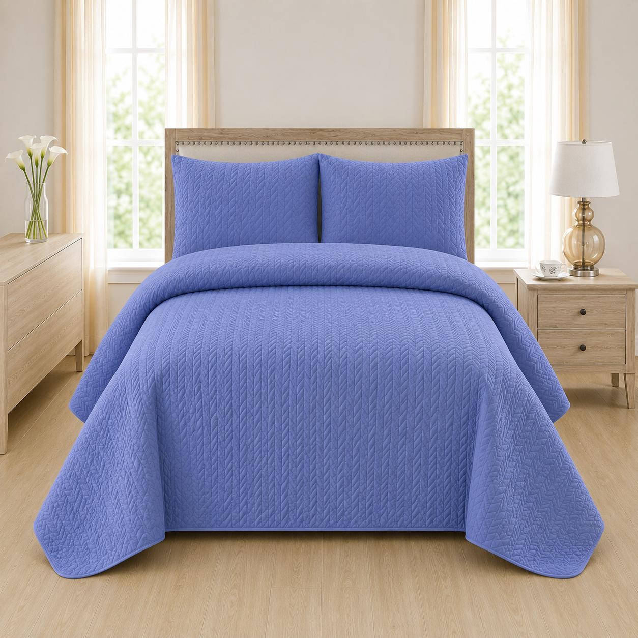 Blue quilted 3-piece bed spread set with two matching pillow shams on a made bed