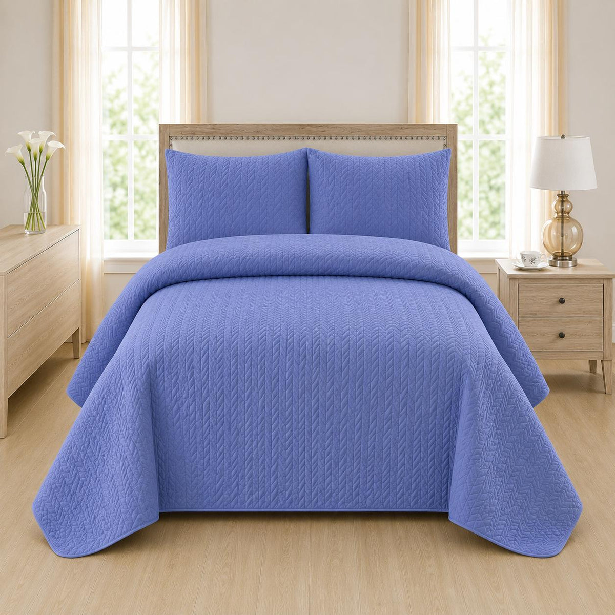 Blue quilted 3-piece bed spread set with two matching pillow shams on a made bed
