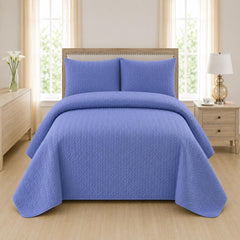 Blue quilted 3-piece bed spread set with two matching pillow shams on a made bed