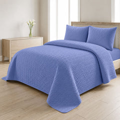 Blue quilted bedspread styled on a bed in a cosy neutral bedroom