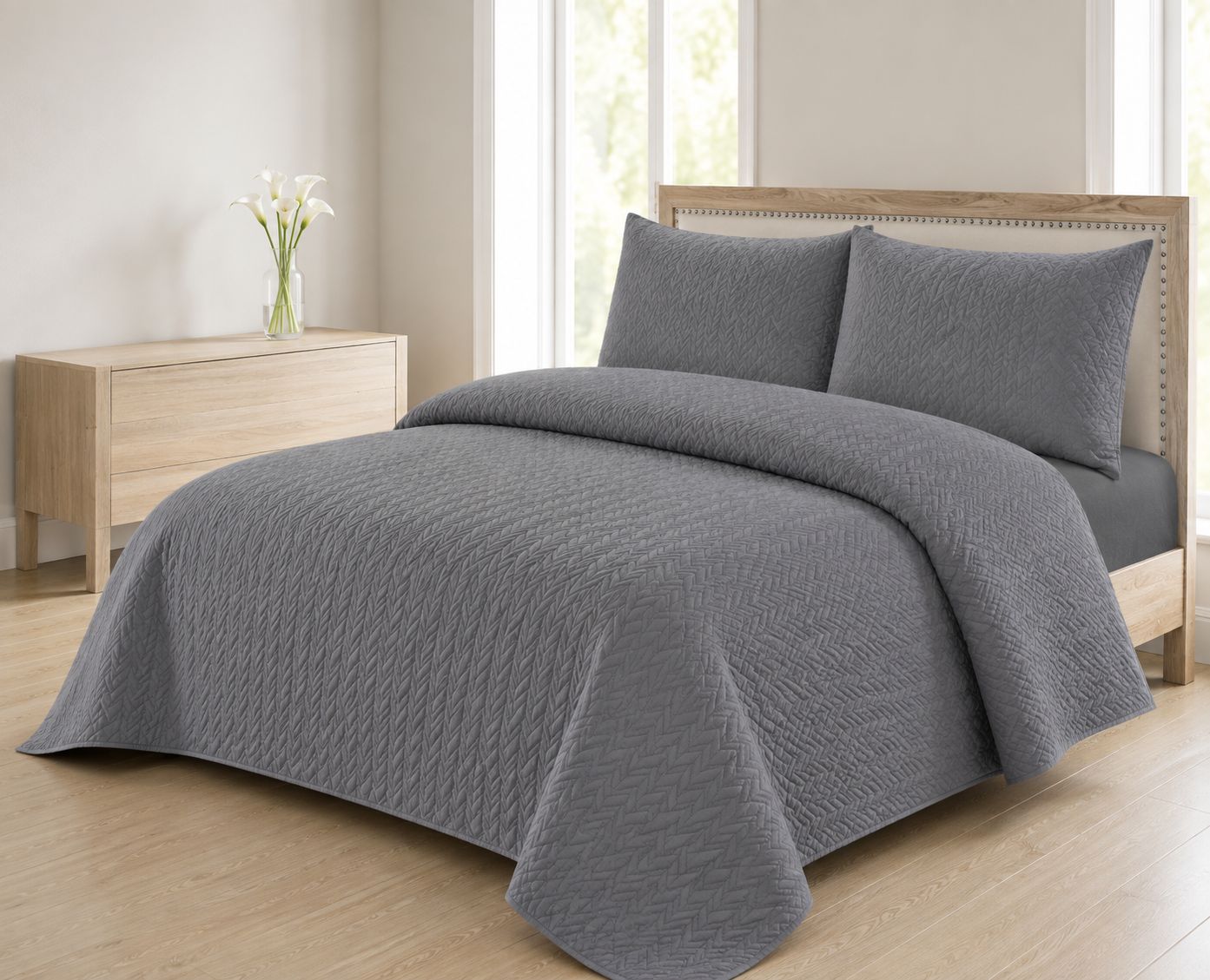 Grey quilted bedspread styled on a bed in a cosy neutral bedroom