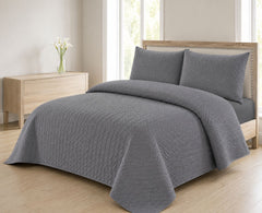 Grey quilted bedspread styled on a bed in a cosy neutral bedroom