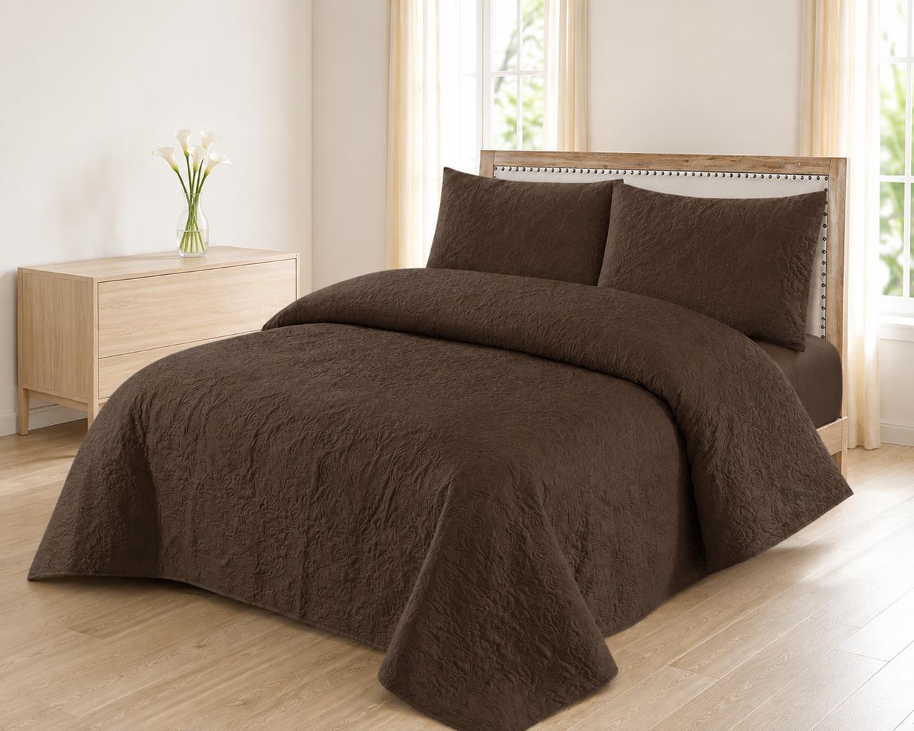 Chocolate brown quilted 3-piece bed spread set with two matching pillow shams on a made bed
