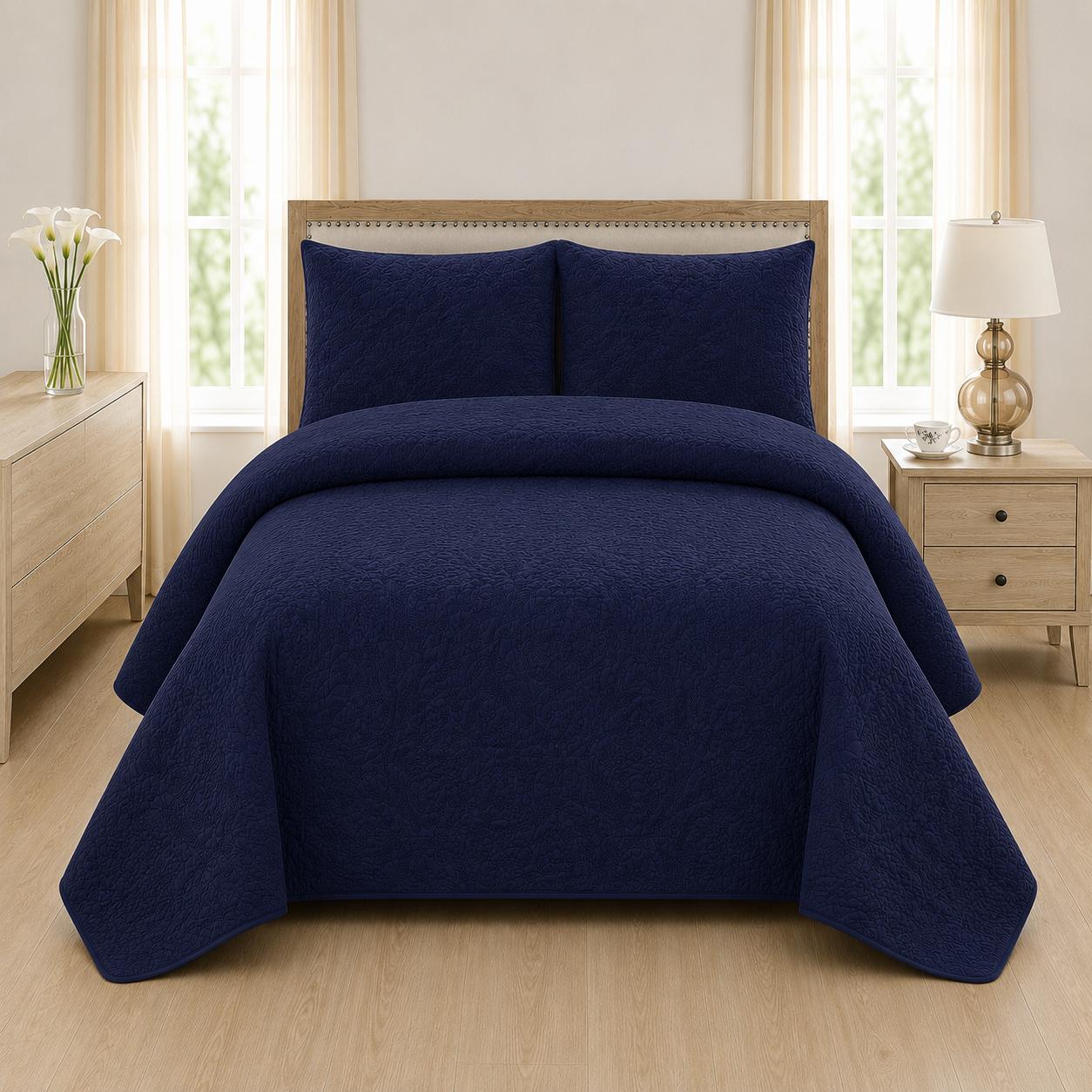 Navy blue quilted 3-piece bed spread set with two matching pillow shams on a made bed