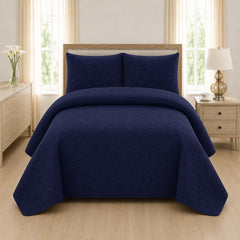 Navy blue quilted 3-piece bed spread set with two matching pillow shams on a made bed