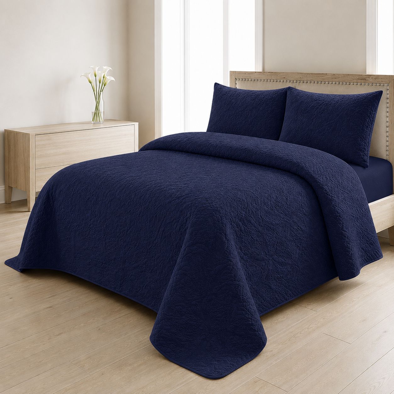 Navy blue quilted bedspread styled on a bed in a cosy neutral bedroom
