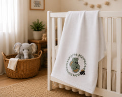The Idea white cotton baby blanket with green woodland bunny wreath embroidery