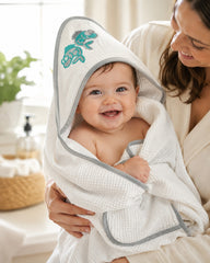 Mother holding baby in fish hooded towel in the bathroom