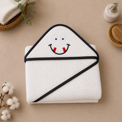 The Idea white folded hooded baby towel with embroidered happy face and dark trim