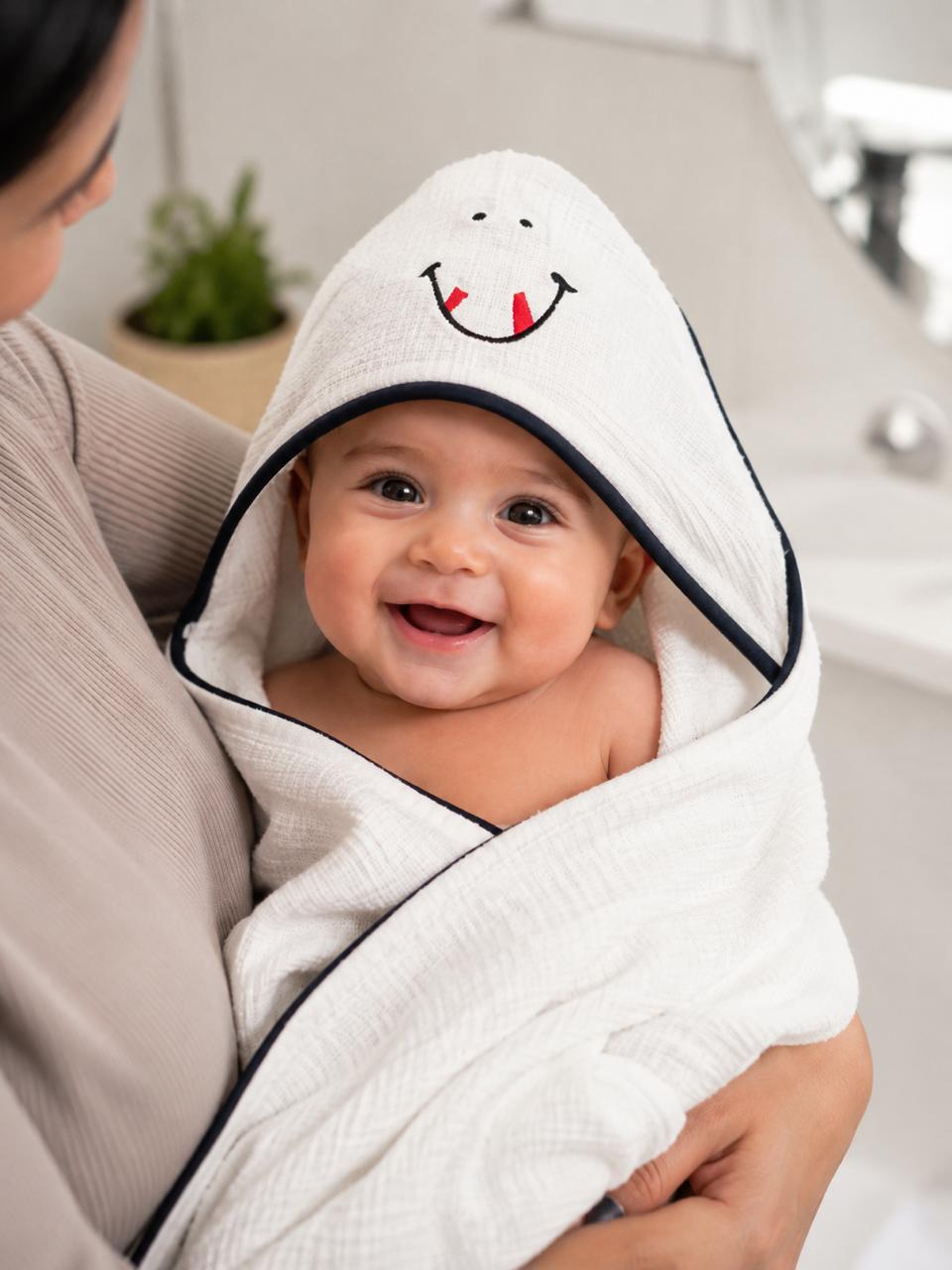 Baby wrapped in The Idea white embroidered hooded cotton towel