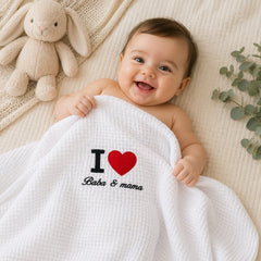 Baby lying under the I Love Baba and Mama embroidered baby blanket