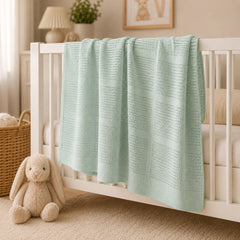 Mint basketweave baby blanket draped on a crib