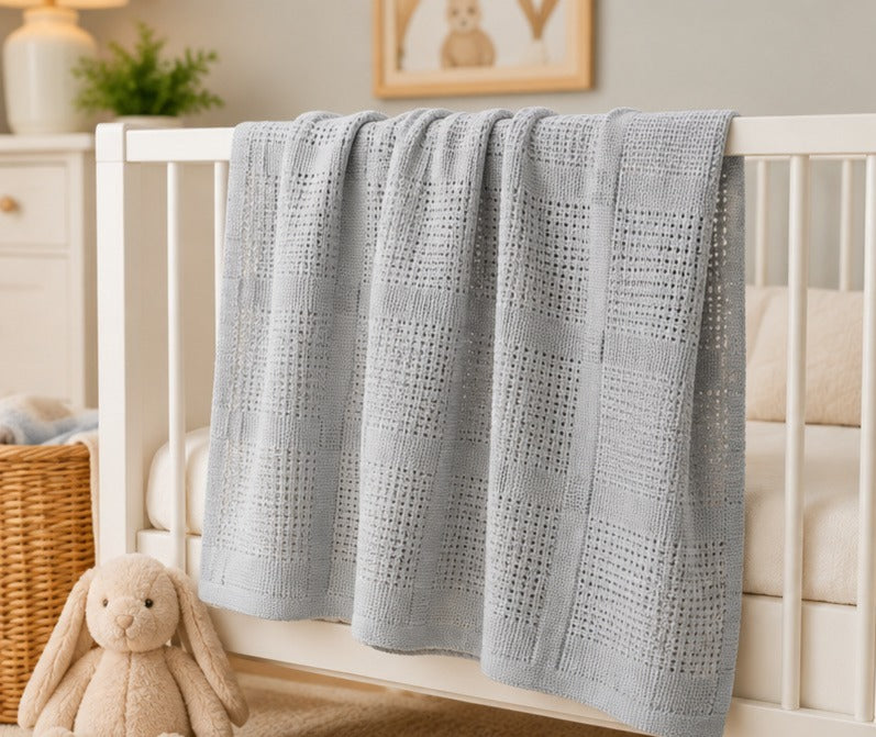 Grey cellular cotton baby blanket draped on a crib