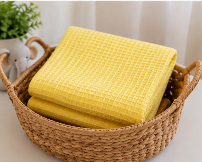 Yellow honeycomb waffle baby blankets folded in a woven basket