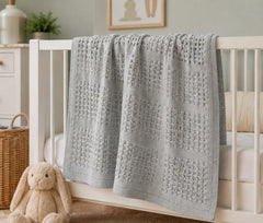 Grey basketweave baby blanket draped on a crib