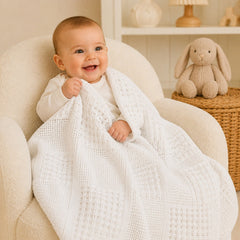 Baby wrapped in white basketweave cotton blanket