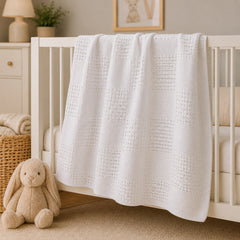 White basketweave baby blanket draped on a crib