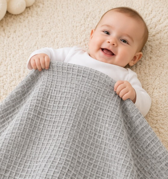 Baby holding a light grey honeycomb waffle cotton blanket