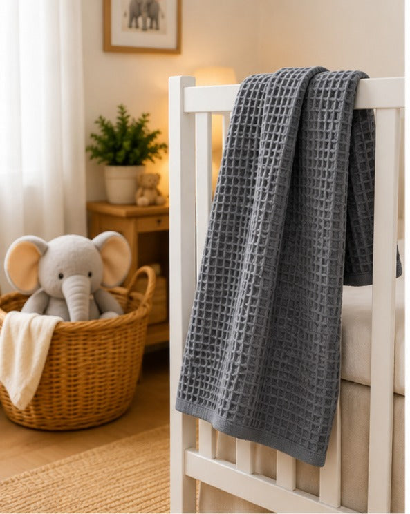 Charcoal honeycomb waffle baby blanket draped on a white crib