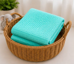 Turquoise honeycomb waffle cotton baby blanket folded in a basket