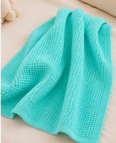 Turquoise honeycomb waffle baby blanket draped on a bed