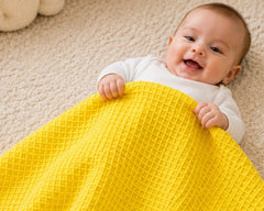 Baby holding a yellow honeycomb waffle cotton blanket