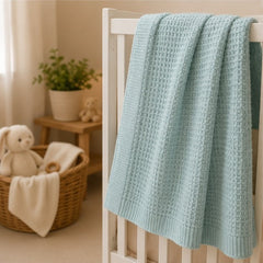 Mint waffle baby thermal blanket draped on a crib